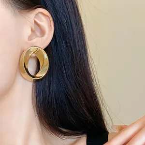 Close-up of large gold twisted hoop earring worn by a model for elegant style