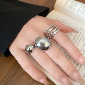 Close-up of minimalist chunky silver-colored rings with smooth metallic finish on hand