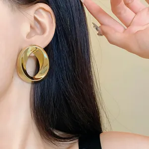 Close-up of a large gold twisted oval earring on a model's ear showing design detail