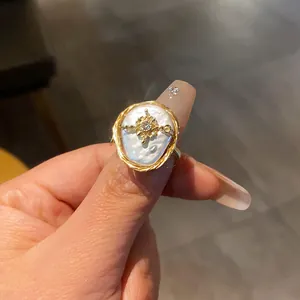 Close-up of irregular baroque pearl ring with gold wire wrap and zircon flower detail