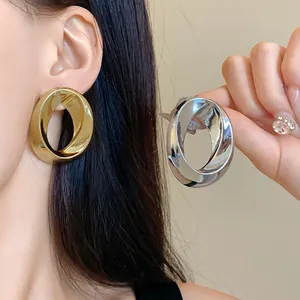 Detailed close-up of chunky twisted metal hoop earrings in gold and silver finishes
