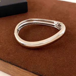 Minimalist irregular curved metal bangle with a polished silver finish for women
