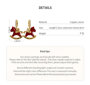 Macro view of red enamel rocking horse earrings with gold details and sparkly zircons.