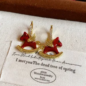 Detailed view of elegant gold-plated red enamel rocking horse hoop earrings with zircon