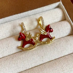 Close-up detail of elegant red enamel rocking horse earrings with sparkling zircon hoops