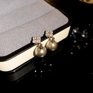 Close-up of elegant flower zircon earrings with pearl drops in a luxury gift box