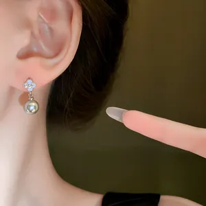 Macro view of exquisite zircon flower and silver pearl drop details on a woman's ear