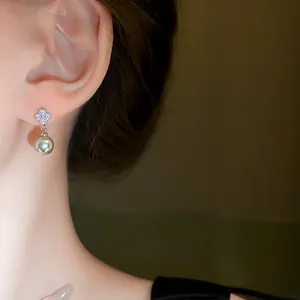 Elegant flower-shaped zircon stud earrings with a dangling grey pearl worn on ear