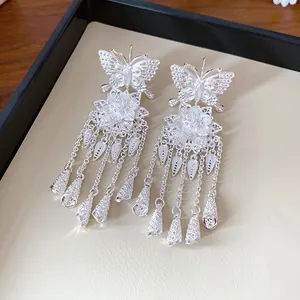 Vue détaillée en gros plan de boucles d'oreilles papillon fleur en argent avec glands