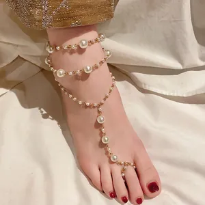 Detailaufnahme einer eleganten mehrlagigen Kunstperlen-Fußkette mit Goldkette und Zehenring