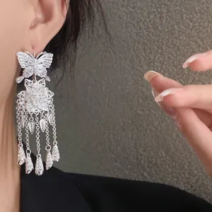 Gros plan détaillé des boucles d'oreilles en argent avec pampilles papillon et fleur