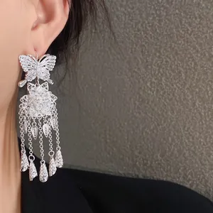 Vue détaillée de boucles d'oreilles argentées ajourées avec papillon et glands
