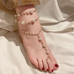 Detailansicht eines eleganten goldfarbenen Fußkettchens mit mehrlagigen Kunstperlen.