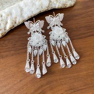 Vue détaillée de boucles d'oreilles filigranes en argent avec papillon et glands