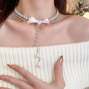 Close-up of elegant pearl and zircon choker with pink ribbon bow detail.