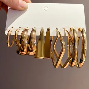 Close-up of assorted gold geometric hoop and stud earrings displayed on a white presentation card