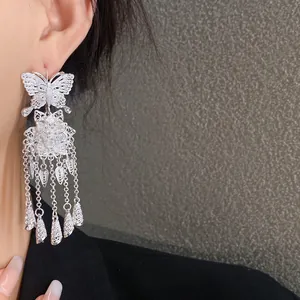 Vue détaillée de boucles d'oreilles ethniques en argent avec papillon, fleur et glands.