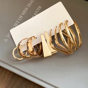Macro shot of assorted minimalist golden hoop earrings set on a white display card