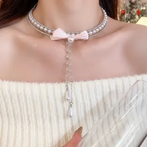 Close-up detail of an elegant pearl choker necklace featuring a pink bow and zircon crystals