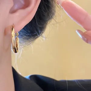 Close-up detail shot of a classic gold-colored hoop earring worn on a person's ear