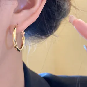 Close-up detail of a polished gold chunky hoop earring elegantly worn on an ear