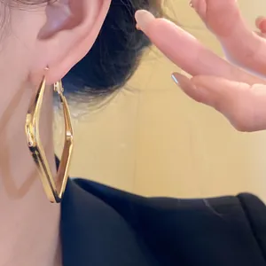 Detailed close-up of minimalist gold geometric rhombus hoop earrings on an Asian model's ear