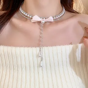 Close-up of elegant pearl choker with pink fabric bow and teardrop dangles