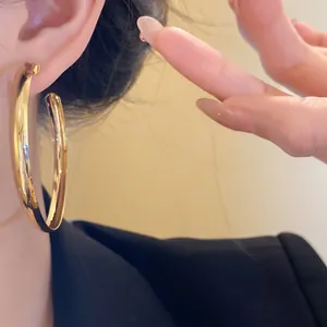 Elegant minimalist large gold hoop earrings with high-polish finish on a model
