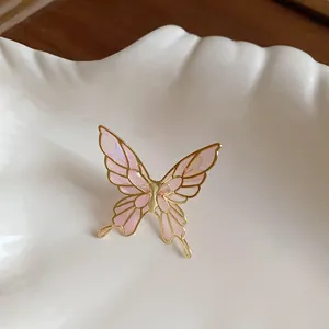 Close-up detail of an ethereal pink butterfly enamel ear clip with a golden metallic frame