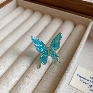 Detailed macro view of a translucent blue butterfly ear clip with gold metal frame