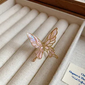 Detail view of an elegant butterfly ear clip with pink iridescent enamel inlay.