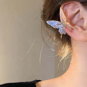 Close-up of an iridescent butterfly ear cuff with golden trim worn on a model's ear