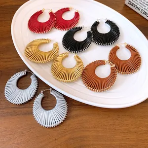 Group of colorful ribbed textured hoop earrings on a white decorative plate.