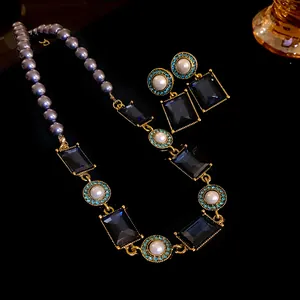 Close-up of vintage jewelry set with blue gemstones and grey pearls on black background