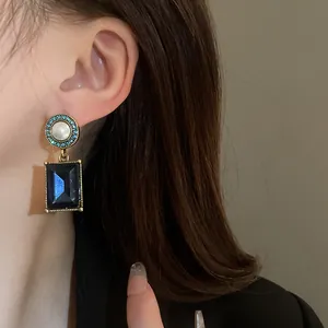Detailed view of elegant vintage French earrings featuring a pearl and blue gemstone.