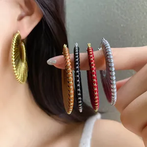 Close-up showing a variety of colorful woven hoop earrings in gold, red, black, and silver