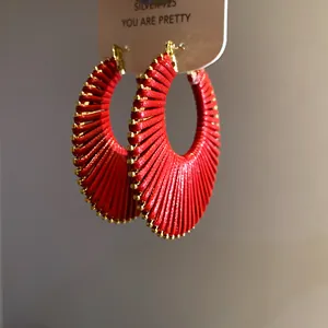 Close-up detail showing texture of red woven raffia hoop earrings with gold edges