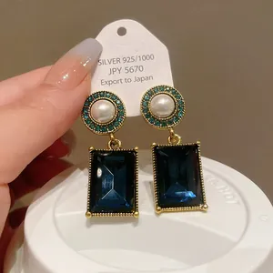 Macro view of vintage French pearl earrings with large square blue gemstone pendants