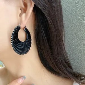 Close-up of a stylish black pleated circular hoop earring worn by a model in a detail shot