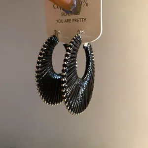 Close-up detail of black woven hoop earrings with S925 silver post on display card.