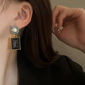 Exquisite vintage gold-tone drop earring featuring blue rhinestones, pearl, and a black square stone