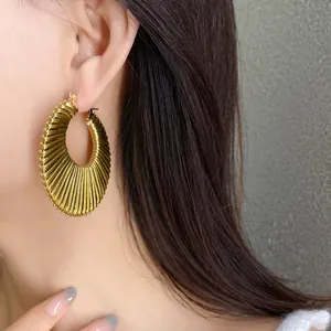Close-up of elegant gold textured crescent hoop earrings worn for a stylish look.