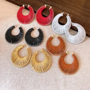 Detailed view of various colorful circular ribbed hoop earrings on a textured fabric background