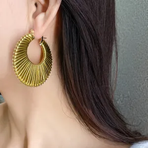Detailed view of an elegant gold pleated hoop earring worn by a model for fashion
