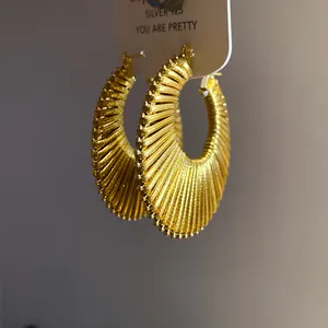 Macro view of gold textured hoop earrings with sunburst pleated design.