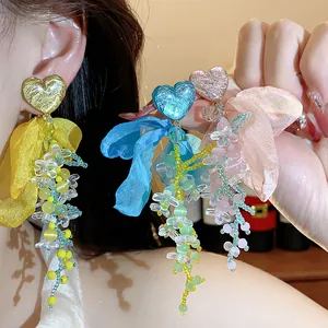 Detail view of heart resin earrings with colorful chiffon flowers and beaded fringe
