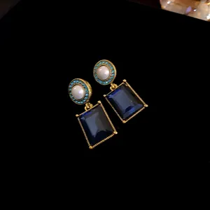 Close-up of vintage French earrings with pearls and deep blue rectangular gemstones