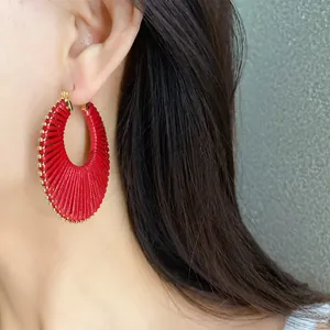 Close-up detail of stylish bold red woven hollow round hoop earrings worn on a model's ear