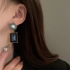 Close-up of vintage palace-style earrings with pearls and blue square gemstones.