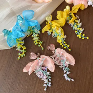 Close-up of elegant resin heart earrings featuring chiffon petals and colorful bead tassels.